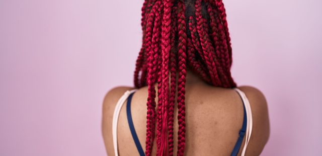 African american woman with braided hair standing over pink background standing backwards looking away with crossed arms