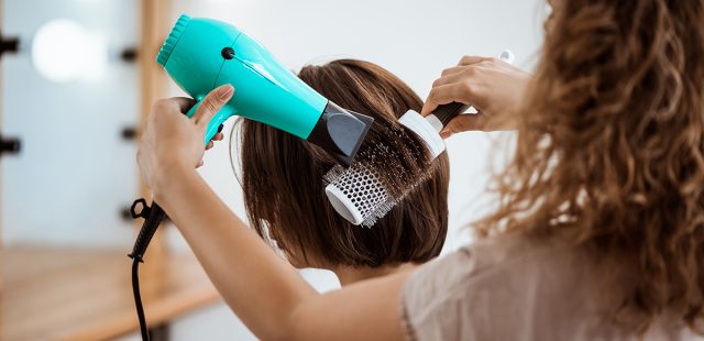 Female hairdresser making hairstyle to brunette girl in beauty salon.